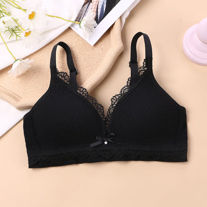 black wireless bralette with seamless lace knitting, fixed cups, and crisscross back straps on a beige backdrop, complemented by white daisies, emphasizing a youthful and elegant lingerie design