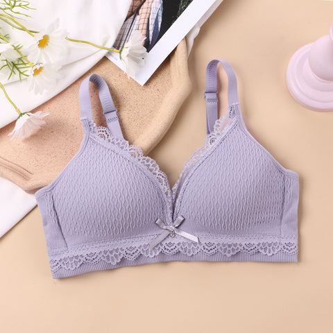 Lavender wireless bralette with seamless lace knitting, fixed cups, and crisscross back straps on a beige backdrop, complemented by white daisies, emphasizing a youthful and elegant lingerie design.