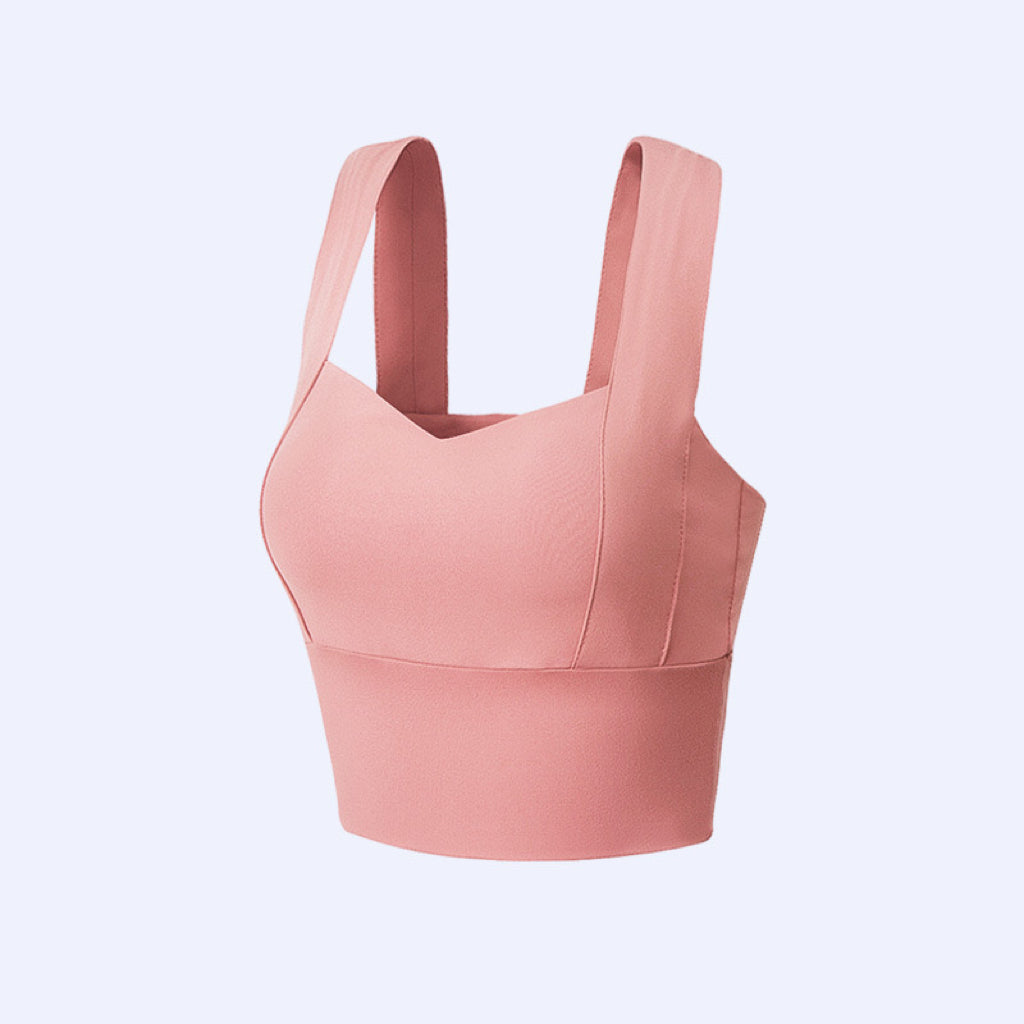 "Confident plus-size woman posing in a rose-pink supportive sports bra"